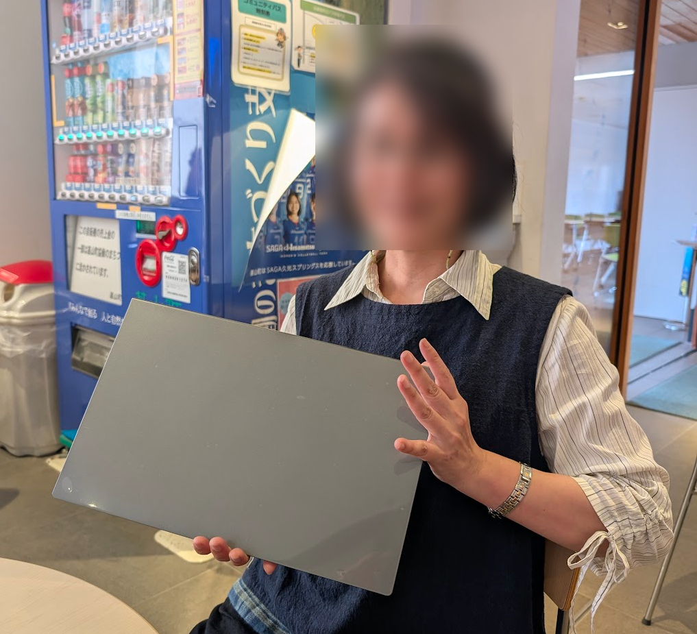 購入したノートパソコンを手に持ち、笑顔で受け取る女性の様子